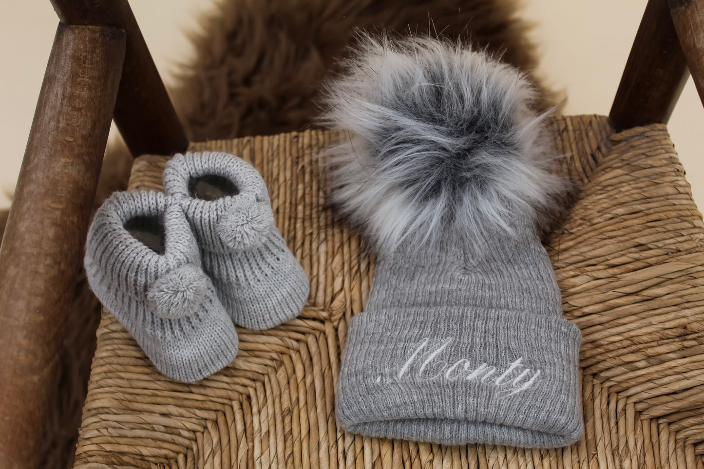 Grey knitted embroidered pom pom hat and matching knitted baby booties