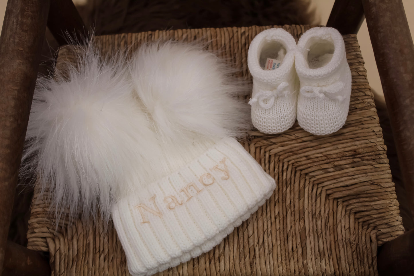 white knitted double pom pom winter hat with matching knitted white baby booties